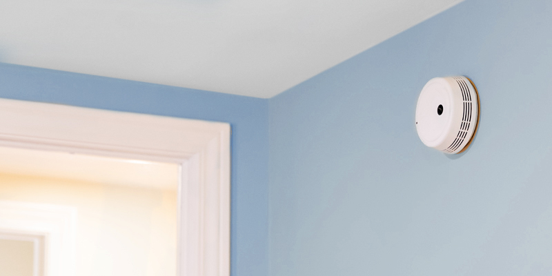 Close-up of smoke detector on sky blue wall.