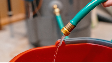 Hose filling up bucket with water