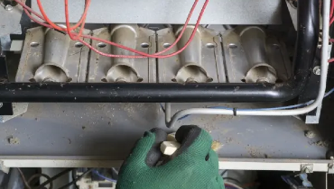 Technician cleaning burner area of a natural gas furnace.