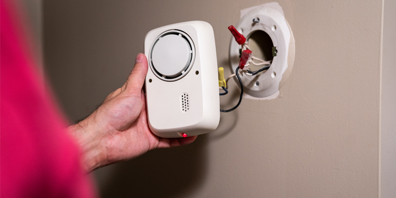 Person assessing hardwired smoke detector