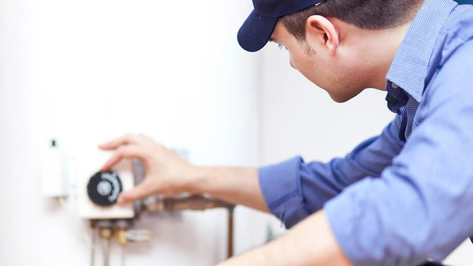 Male Aire Serv technician in baseball cap and blue shirt adjusting meter.