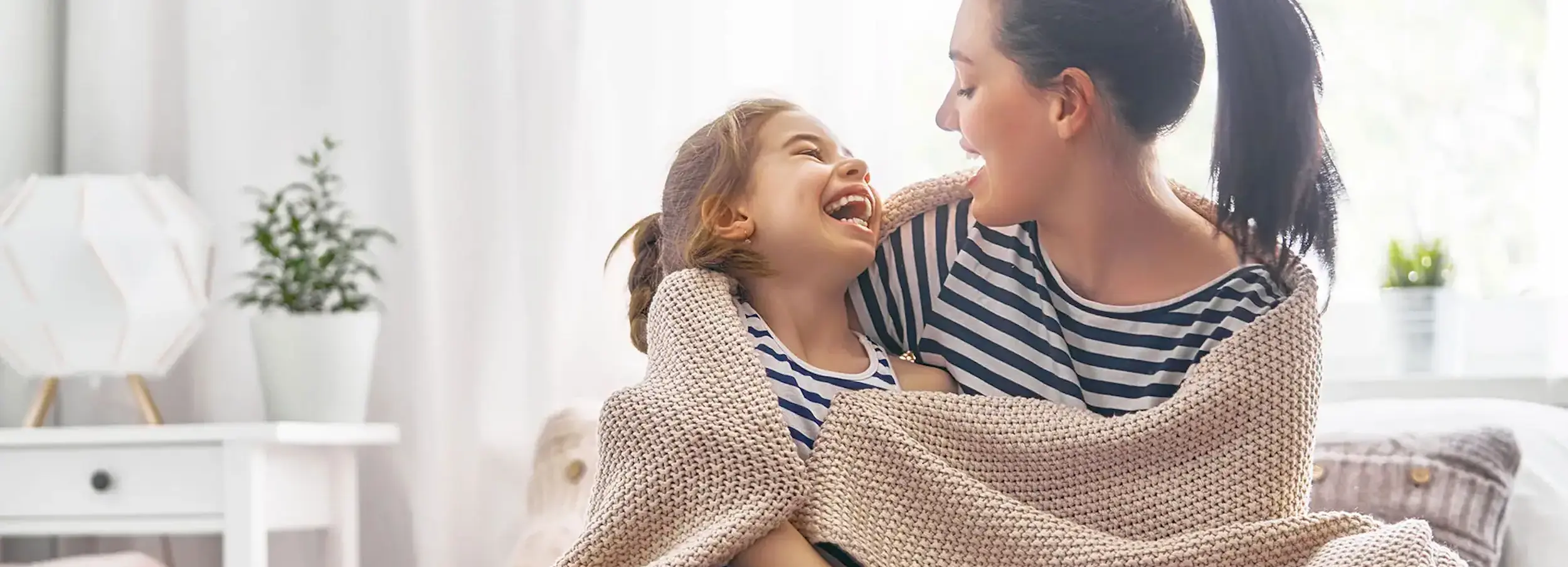 Laughing mother and daughter wrapped in a blanket.