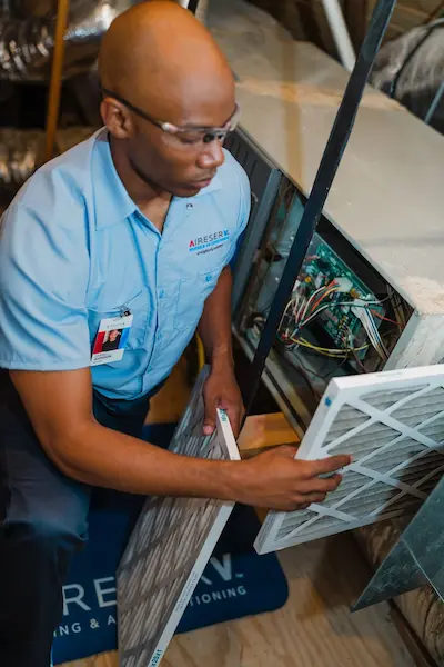 Male HVAC technician replacing air filters.