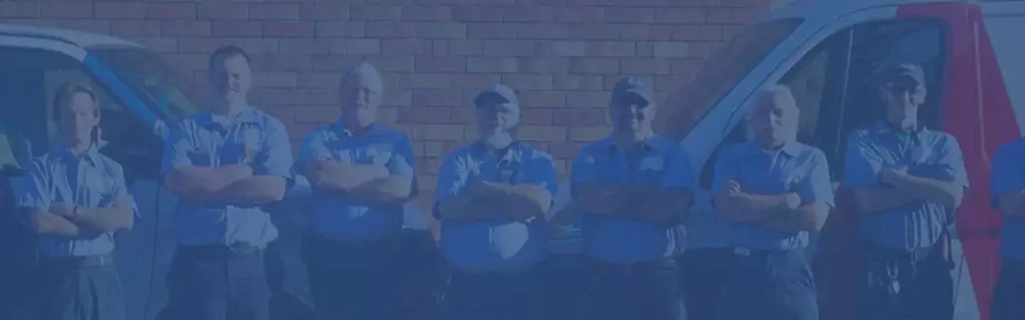 Row of Aire Serv technicians standing with arms crossed between pair of branded vans.